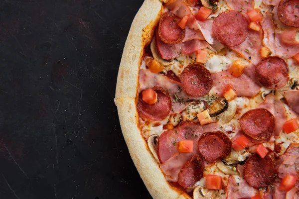 Close up view of pizza with ham, bacon, sausage, tomato and champignon