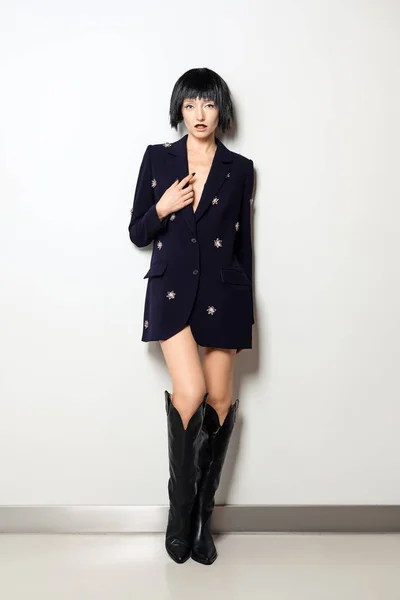파란색 재킷에 보석 장식 이 있고 넓은 부츠를 신은 검정 색 밥 헤어 스타일의 패션 모델 — 스톡 사진