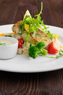 Pilav, dolma biber ve roka ile sahanda kızartılmış Zander 'ın koyu ahşap arka planda mayonez sosuyla servis edilmiş fotoğrafı.