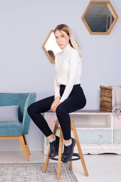 Retrato de comprimento total da jovem sentada na cadeira na sala de estar — Fotografia de Stock