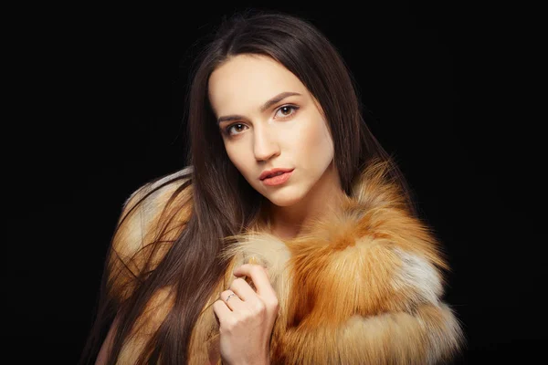 Beautiful happy girl in fur coat over black background — Stockfoto