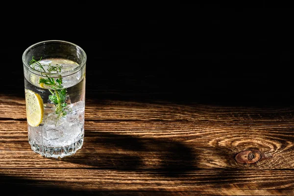 Buzlu ve limonlu karbonatlı soğuk su ahşap masaya uzun gölge düşürüyor. — Stok fotoğraf