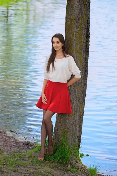 Retrato de una chica en falda roja y blusa blanca apoyada contra —  Fotos de Stock