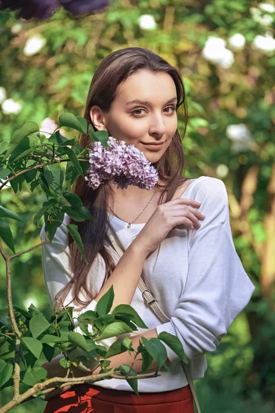 Retrato al aire libre de hermosa chica sonriente de pie entre arbustos lila — Foto de Stock