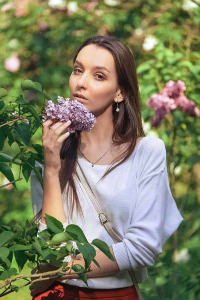 Retrato al aire libre de hermosa chica sonriente de pie entre arbustos lila — Foto de Stock