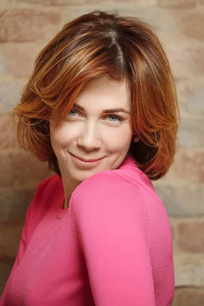 Evde kısa kızıl saçlı orta yaşlı bir kadının portresi.