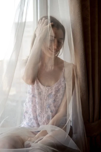 Beautiful girl in pajama sitting on windowsill — 스톡 사진