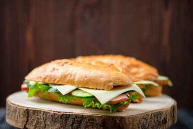 Jambonlu, salatalıklı, tahtada çedar peynirli Hunter sandviçi.