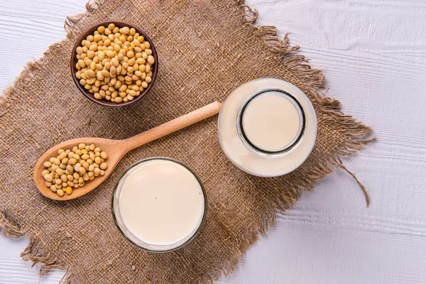 Vista superior de la botella de leche de soja con soja en la mesa blanca — Foto de Stock