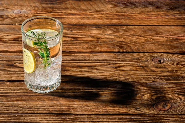 Buzlu ve limonlu karbonatlı soğuk su ahşap masaya uzun gölge düşürüyor. — Stok fotoğraf