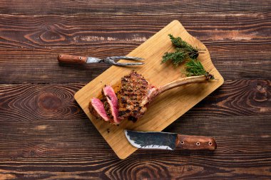 Overhead view of medium rare cowboy steak on wooden cutting board