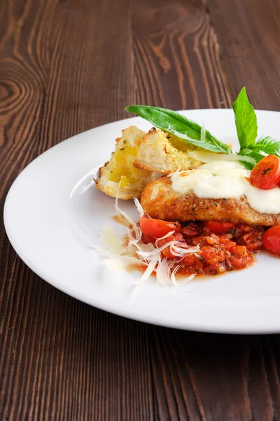 Vista de perto de filé de frango assado com tomate cereja, parmesão e crouton no fundo de madeira escura — Fotografia de Stock