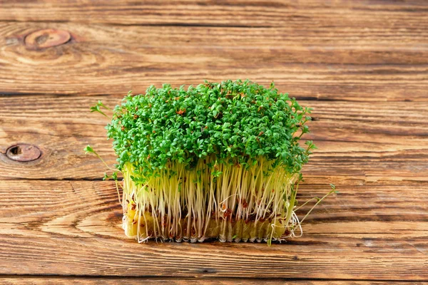 Verse microgreens. Stukjes waterkers op houten ondergrond. — Stockfoto