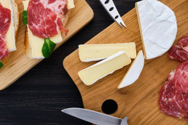 Koyu ahşap masada füme domuz pastırmalı Camembert sandviçi..