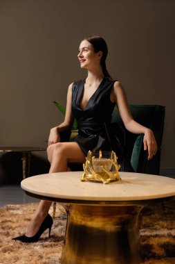 Sahte deri elbiseli şirin ve mutlu bir kız evdeki kahve masasının yanında oturuyor.