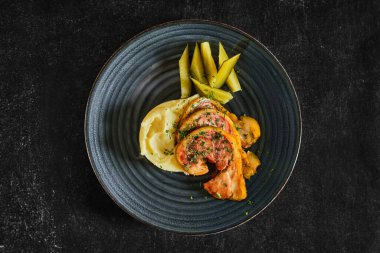 Fırında domuz pastırması, patates püresi ve salatalık turşusu.