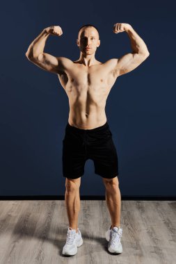 Vücut geliştirici kaslarının gevşediğini, güçlü kollarının ve kaslarının kasıldığını gösteriyor.