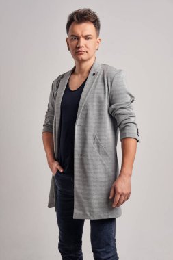 Yün ceket, siyah gömlek ve kot pantolon giyen yakışıklı bir adamın portresi