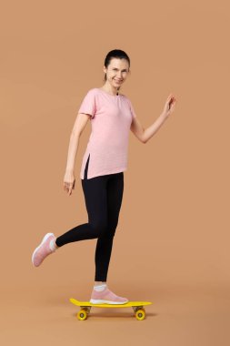 Bej arkaplanlı kaykaycı kız.