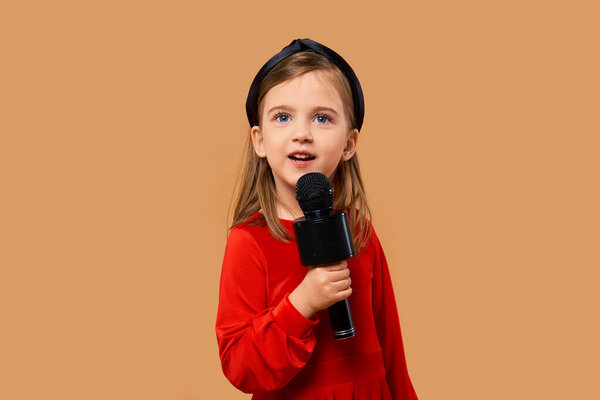 Artistic girl in red dress singing in karaoke microphone