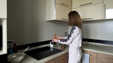 Pijamalı kız mutfakta kahve hazırlıyor.