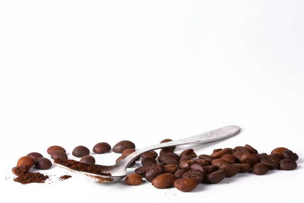 Зерно кофе, бобы и кофейная ложка на белом фоне. Крупный план — стоковое фото