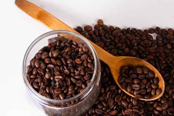 Дерев'яна ложка з кавовими зернами та скляною ємністю — стокове фото