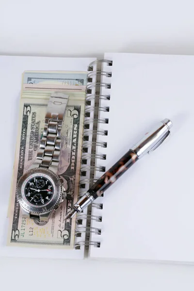 Reloj clásico con un dólar, modelo en billetes de dólar y bolígrafo, notebook . —  Fotos de Stock