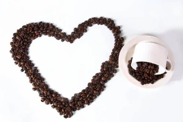 Grãos de café na forma de corações com uma xícara — Fotografia de Stock