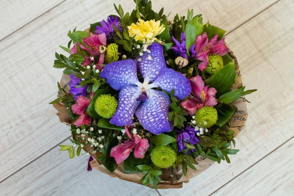 Bouquet of flowers in paper on wood. Aerial view.