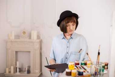 Gülümseyen ve bir görüntü boya fırça, tutan genç kadın ressam