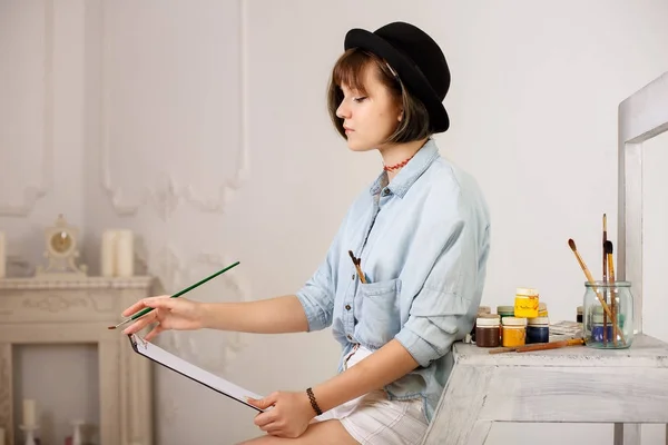 Jovem pintora segurando escova, sorrindo e pintando um pictur — Fotografia de Stock