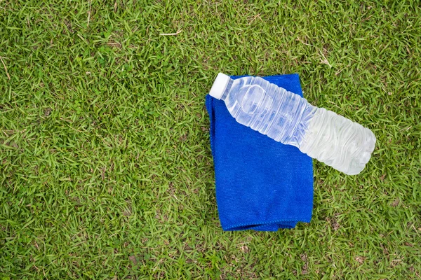 Parte superior - ver botella de agua y toalla con fondo de hierba — Foto de Stock