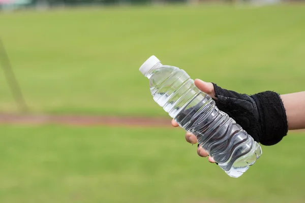 Mano de mujer sana con guantes Sostener la botella de agua dulce — Foto de Stock