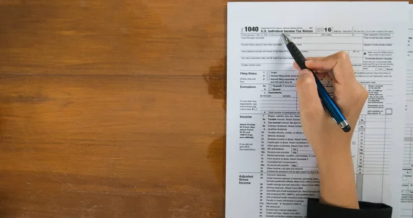 Vista superior de la pluma de mano rellene los detalles en los formularios de impuestos p — Foto de Stock