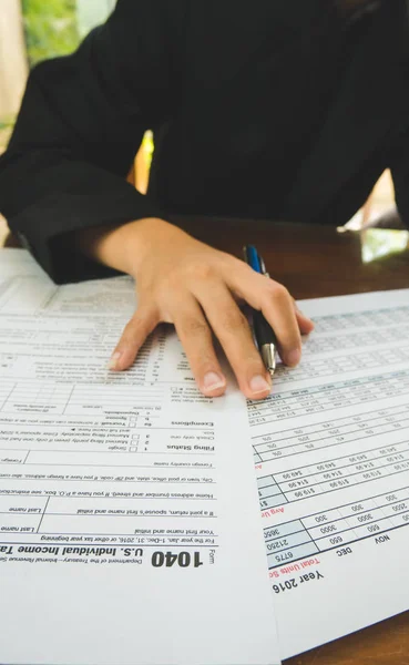 Business woman hand hold on the tax forms paper in business conc