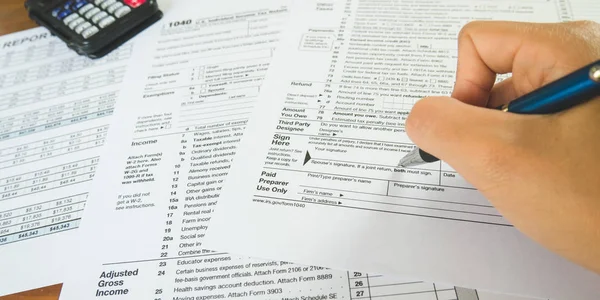 Sostenga la pluma en el punto de la muestra en el papel de los formularios de impuestos en el negocio c — Foto de Stock