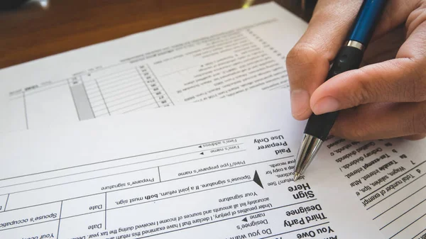 Hand hold pen on sign point on the tax forms paper in business c