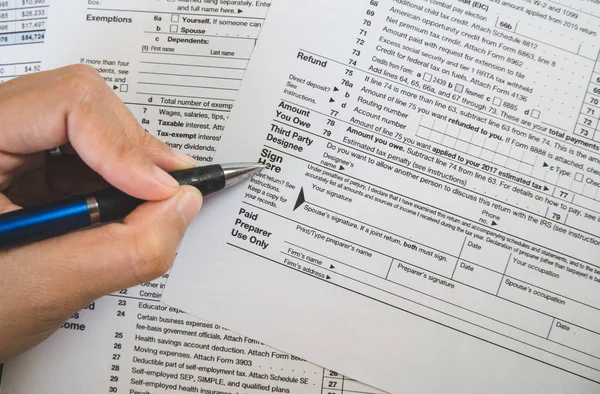 Hand hold pen on sign point on the tax forms paper in business c