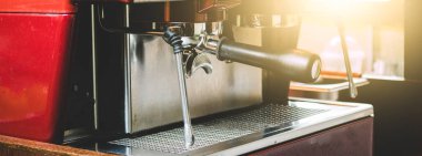 Profesyonel bir barista kahve makinesini müşterinin siparişiyle kahve yapmak için kullanır. Kahve dükkanı eski moda, güneş ışığıyla süslenir.