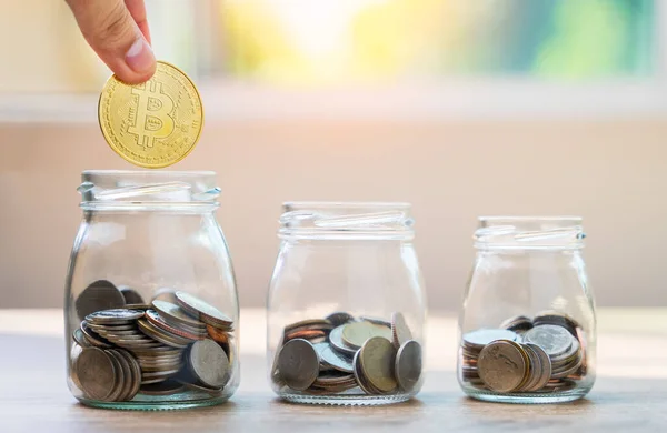 Tasarruf kavramları, tasarruf, turizm, yatırım, acil durum, emeklilik gibi harcamalara harcanmak üzere cam şişelere para koymak için el ele tutuşan bitcoin kavramlarını bulanık arka planı olan ahşap masaya koyuyor 