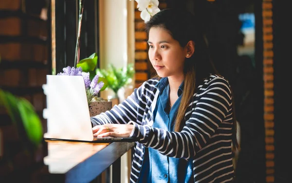 Blogger Asian Women\'s writers are using laptops at the coffee shop to write, share stories or travel reviews to her social media followers in travel concept , vintage style