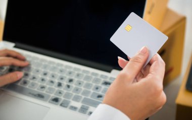 Girişim sahibi küçük işletmeler, çevrimiçi satış kavramında işyerindeki birçok paket paketi ile çevrimiçi işlem yapmak için kredi kartını ellerinde tutuyorlar.
