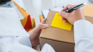 Bir çok paket paketli küçük işletme sahibi ile başlat İşyeri online satış kavramında denetim listesi kağıdı ile göndermeden önce müşteri adresleri yazmaktadır