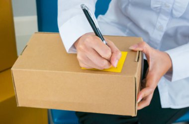 Bir çok paket paketli küçük işletme sahibi ile başlat İşyeri online satış kavramında denetim listesi kağıdı ile göndermeden önce müşteri adresleri yazmaktadır