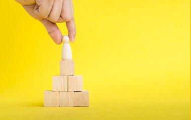 El, insan kaynakları yönetimi kavramlarında istiflenmiş ahşap figür üzerinde tahta figürü seçiyor veya seçiyor. Ekip Çalışmaları: Ekip Liderliği, İş Süreci ve Sarı gergedan üzerine Rekabet ve Boşluk Kopyalama