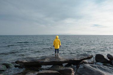 Sarı yağmurluk standı önünde deniz, insan
