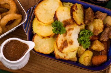 Sığır eti bir tepesi dilimlenmiş patates, çeşitli sebze ve şişman hırpalanmış soğan halkaları ve soğan sos bir sürahi maya ekmek ile servis ile İrlandalı yiğit Stewa tabak İrlandalı stout içinde sığır eti. A St Patricks Günü favori.