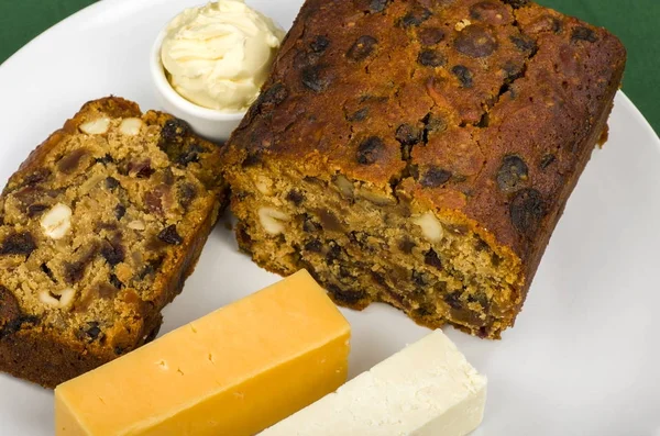 Irish Stout Fruitcake.Irish Stout Fruitcake with a slice cut and two pieces of cheese and a portion of butter.