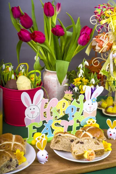 Easter Hot Cross Buns.Selection of Easter Hot Cross Buns with chocolate Easter Eggs and spring flowers with novelty chicks.